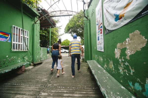 A family walking down a street between two green buildings