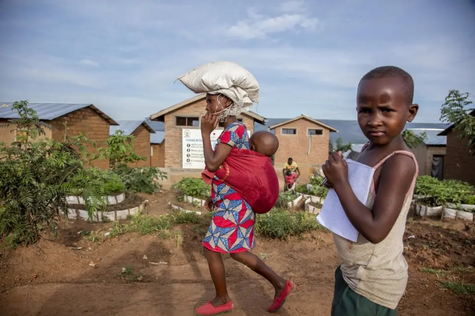 Une femme et un enfant réfugiés burundais passent devant une école du camp de Mahama à Kirehe, dans l’est du Rwanda, qui assure l’éducation aux enfants des communautés réfugiées et d’accueil