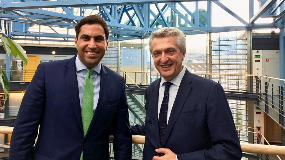 Two men in suits stand next to each other smiling a year before the coronavirus crisis 