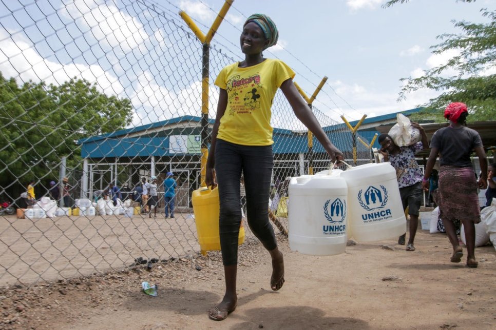 A woman is carrying three jugs of water