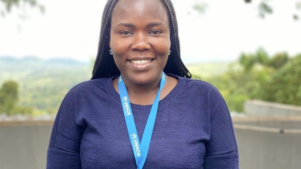 A portrait of a smiling woman with a UNHCR branded lanyard around her neck 