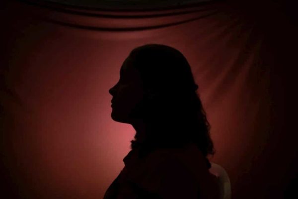 Silhouette of a woman behind a red fabric