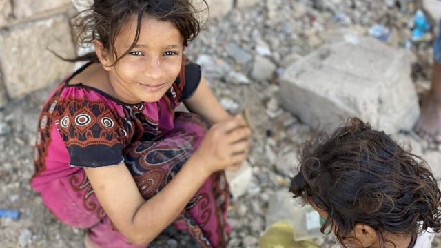 Sur cette photo de février 2020, Ipteehal, 9 ans, joue avec sa soeur à l'extérieur du bâtiment inachevé où elles vivent avec d'autres familles déplacées à Al Mukalla, au Yémen