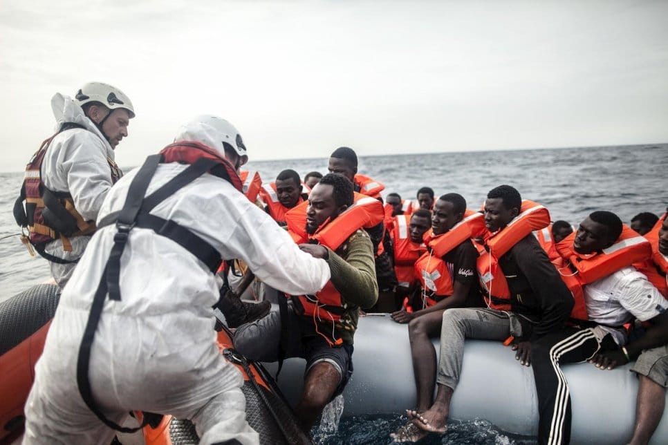 A group of people being rescued from an inflatable life raft on the Mediterranean