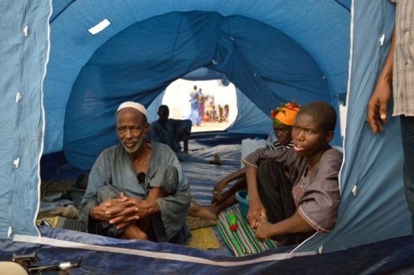 Three people sitting in a blue tent