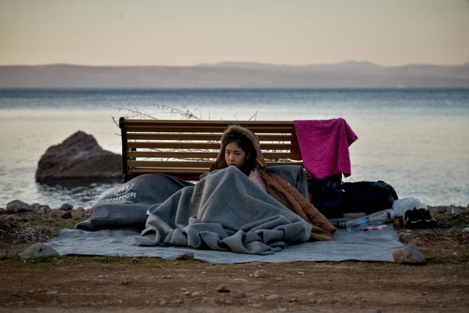 Une jeune fille s’abrite sous une couverture sur la plage de Lesbos en Grèce, le 2 mars 2020. Elle venait de traverser la mer Égée depuis la Turquie à bord d’un canot pneumatique