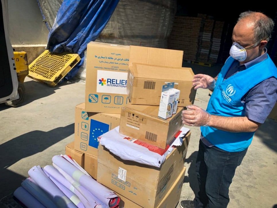 A UNHCR staff member inspects and packs aid items – including soap, disposable paper towels and thermometers – to distribute to refugee settlements in Iran as part of the COVID-19 response
