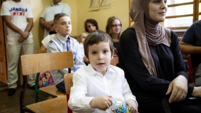 Raisa, une demandeuse d'asile originaire de Tchétchénie, est assise à côté de son fils Yusuf, âgé de quatre ans, lors de la première assemblée de la rentrée à Berezówka, Pologne, septembre 2018