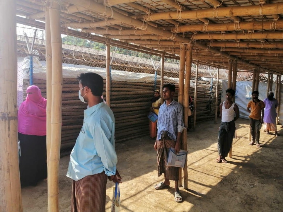 Des réfugiés rohingyas appliquent les mesures de distanciation sociale dans un point de distribution d’un camp à Cox Bazar, au sud-est du Bangladesh
