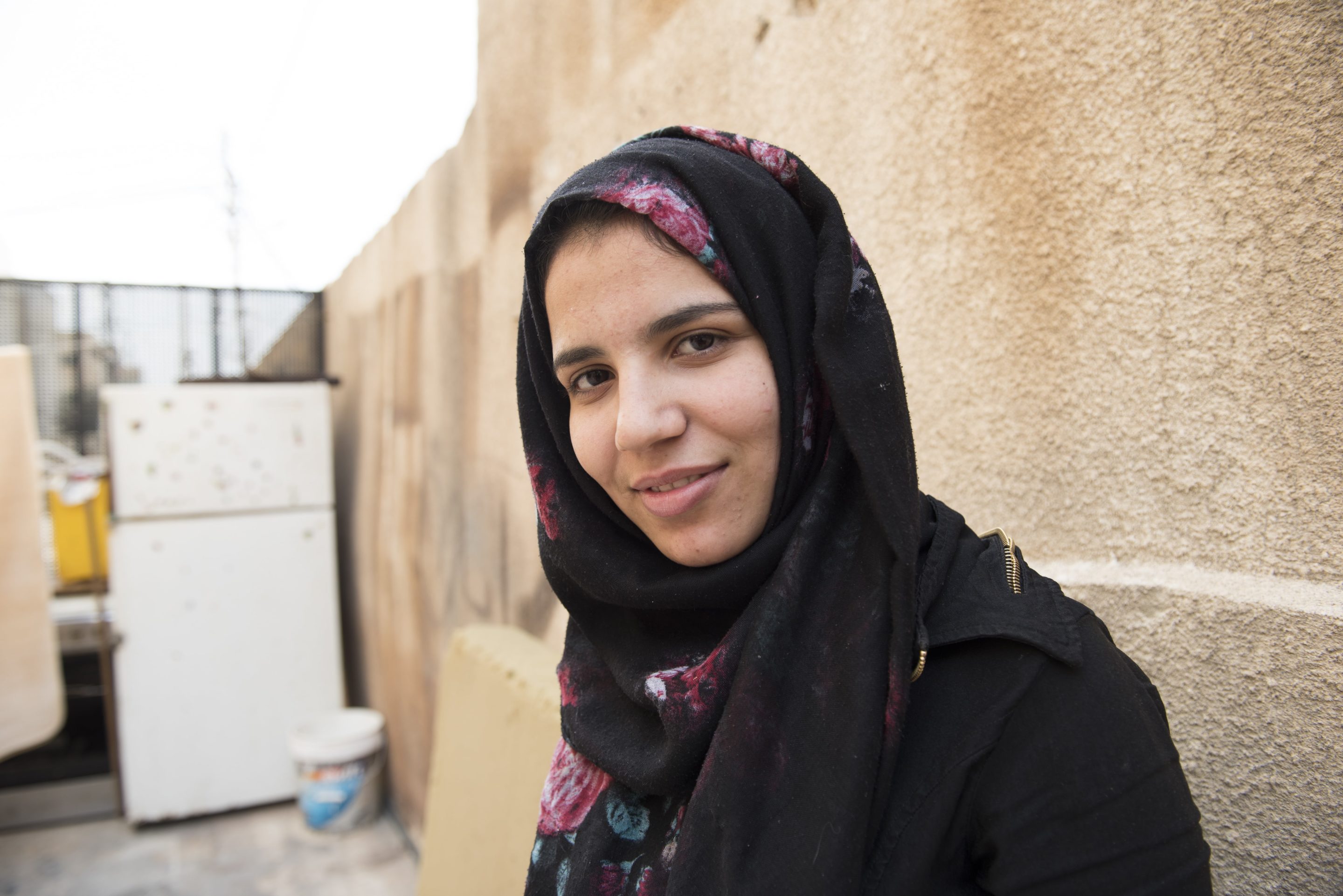 A woman in a black hijab smiles for the camera