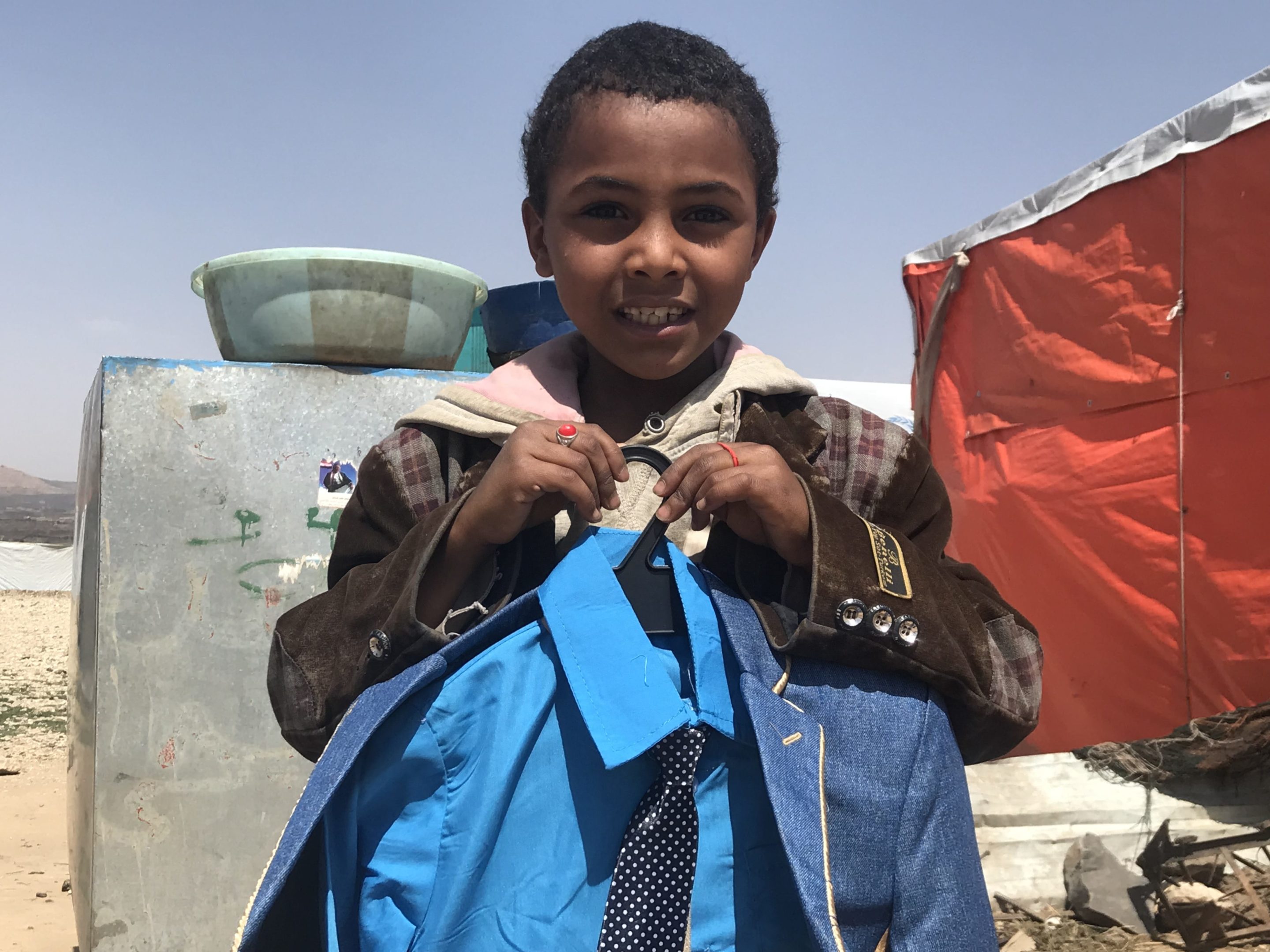 A young boy clutches new clothes to his chest
