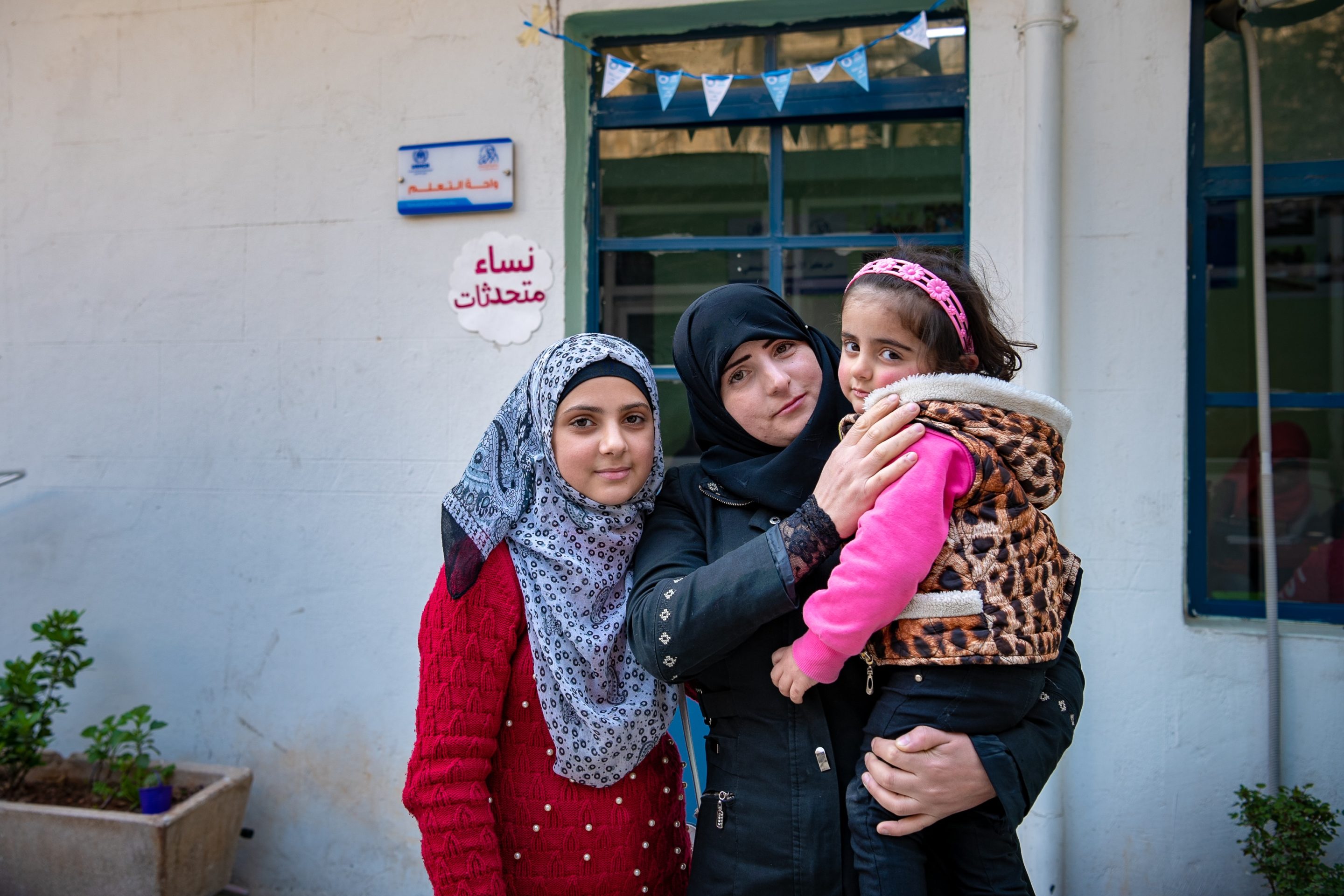 A mother with her two daughters pose for a picture in front of a doorway