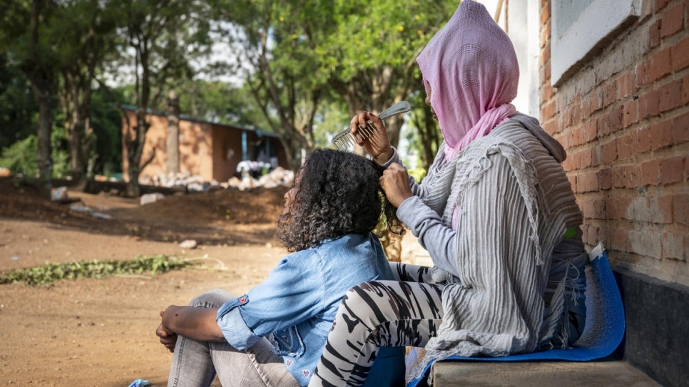 Eritrean refugee Samrawit* braids her friend's hair at the UNHCR Emergency Transit Centre in Gashora, Rwanda