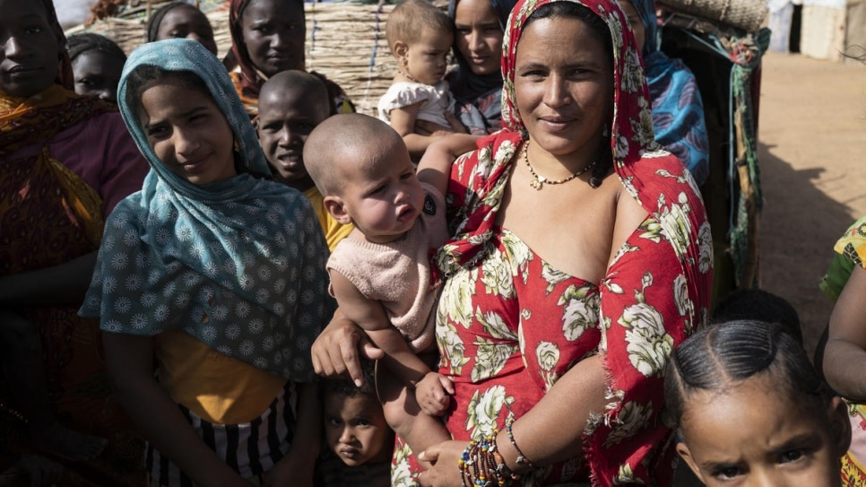 Fatima holds her baby among fellow Malian refugees in Goudoubo camp, Burkina Faso as they wait for dignity kits to be distributed