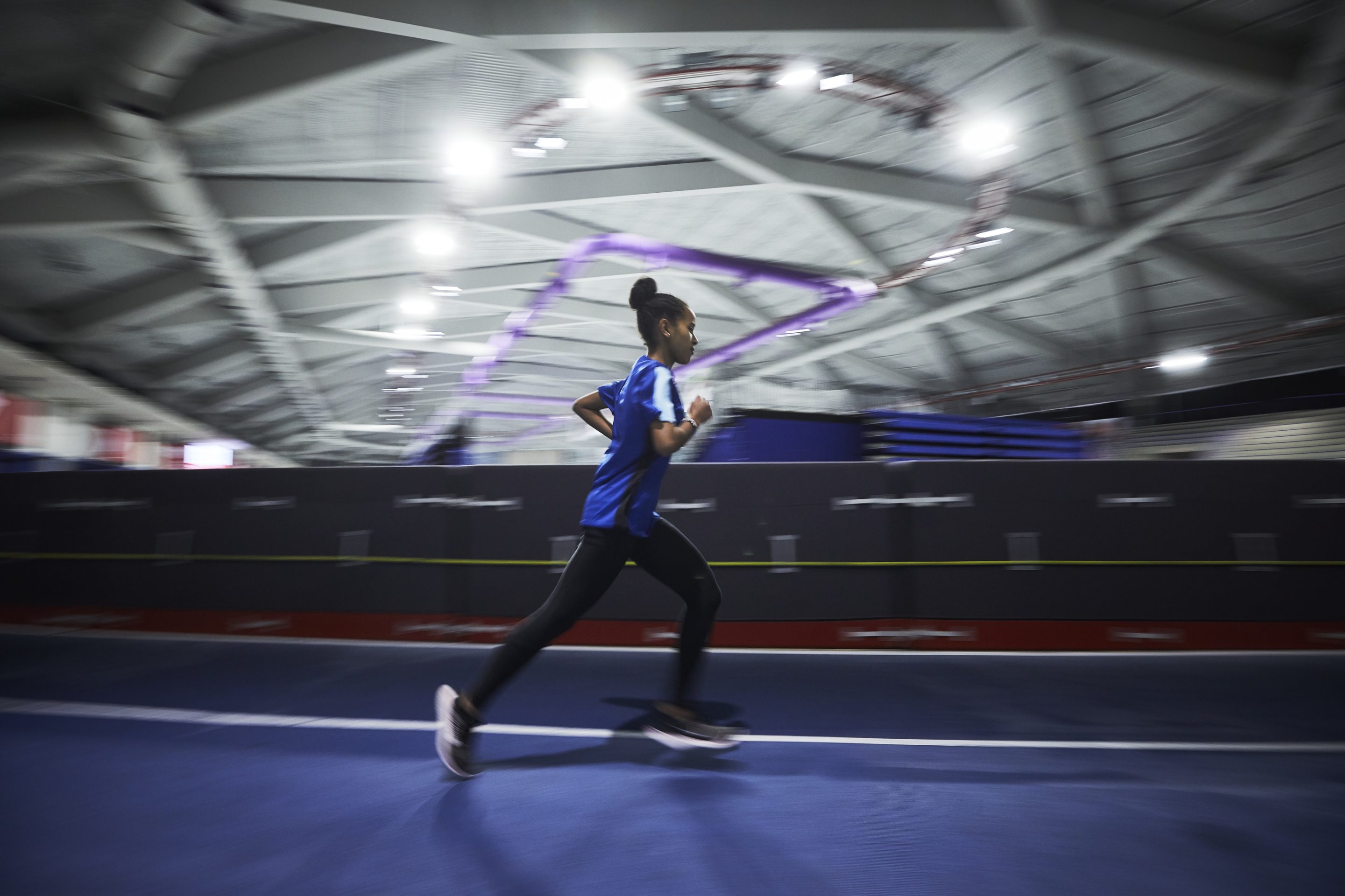 A young woman runs on an indoor track
