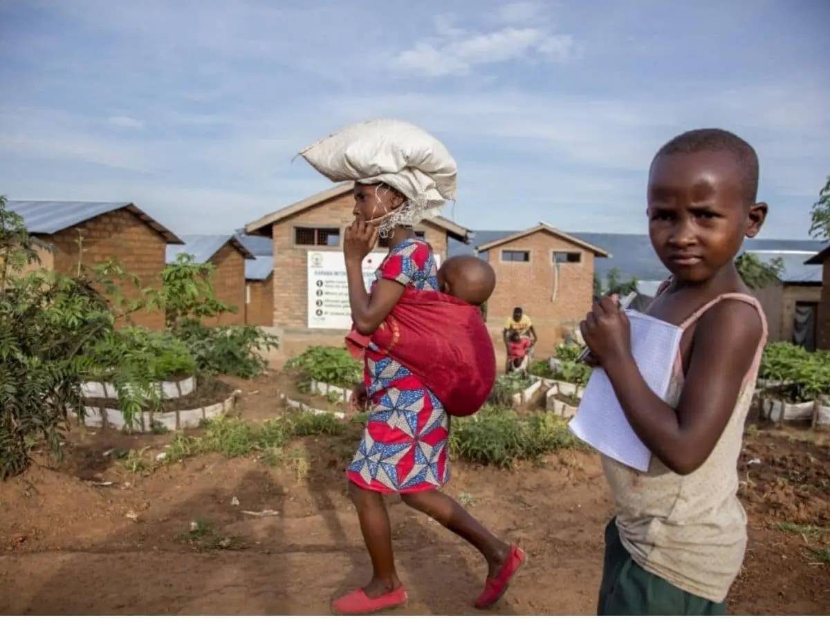 A Burundian refugee woman and child walk past a school at Mahama camp in Kirehe, eastern Rwanda, that provides education to children from the refugee and host communities