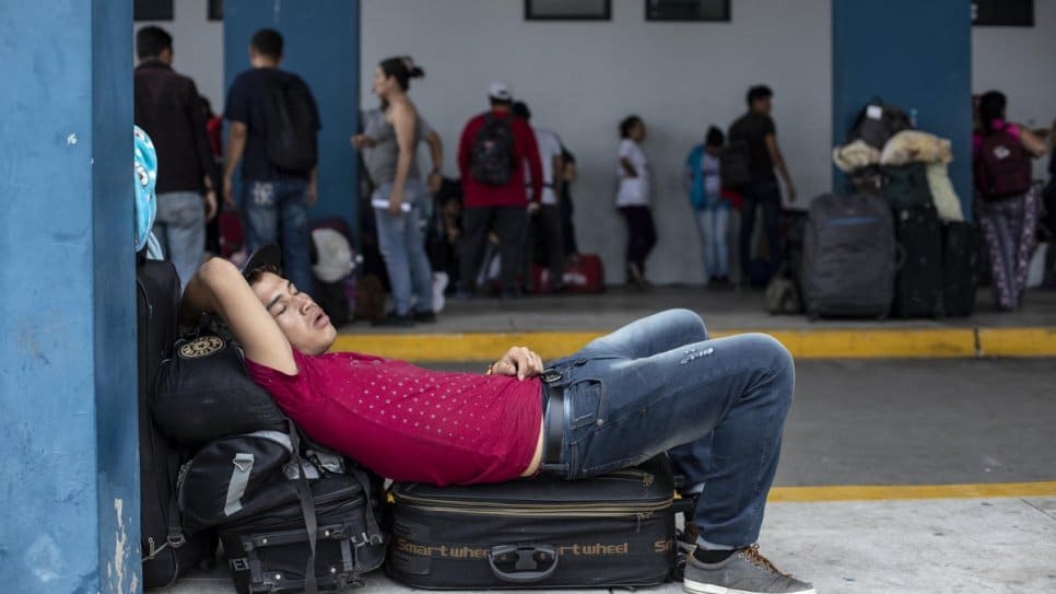 After a long journey, an exhausted Venezuelan man sleeps at the Ecuador-Peru border, waiting for entry into Peru, on 13 June, 2019