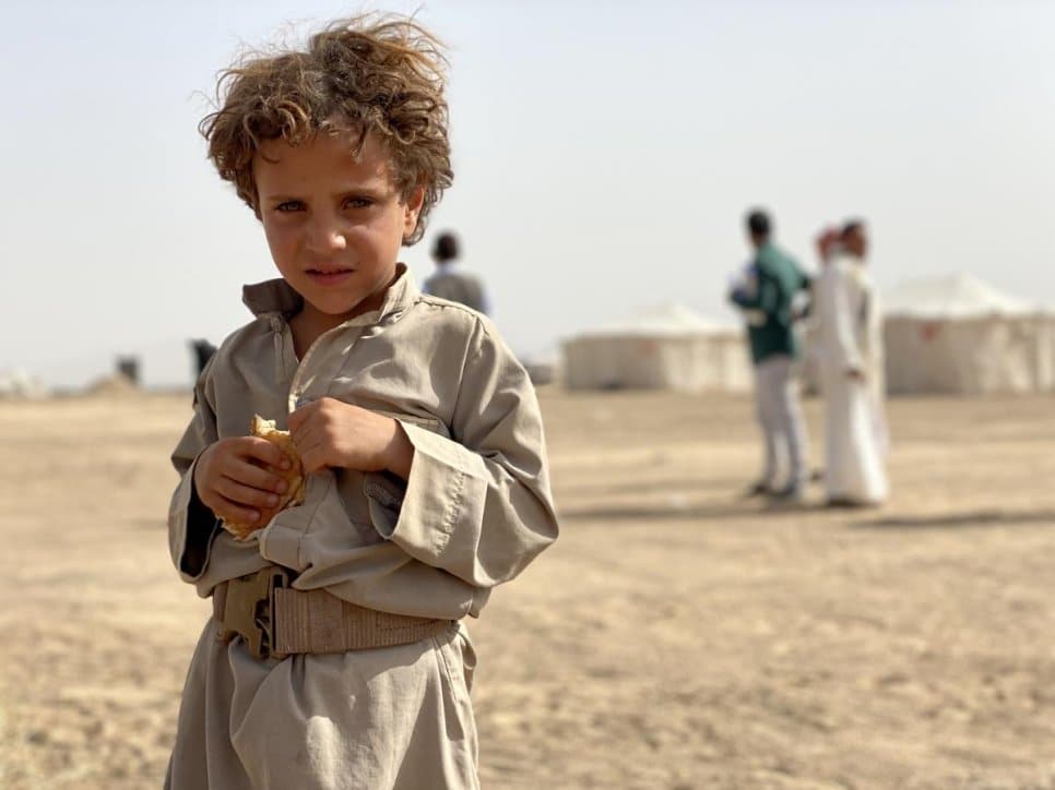 A five-year-old Yemeni boy stands outside a site for internally displaced people in Marib, Yemen, where conflict has forced thousands to flee