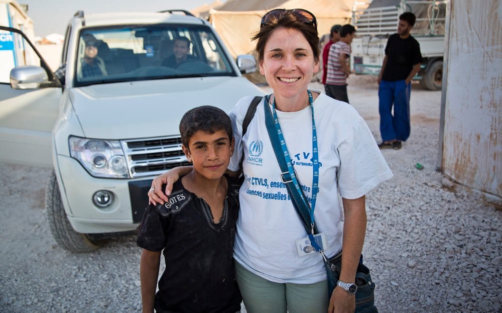 A woman stands with her arm around a child