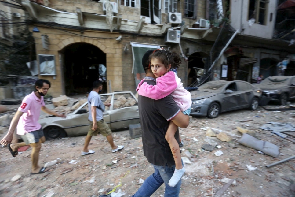 Un homme transporte un enfant blessé vers un lieu sûr, suite à une explosion massive au port de Beyrouth, Liban