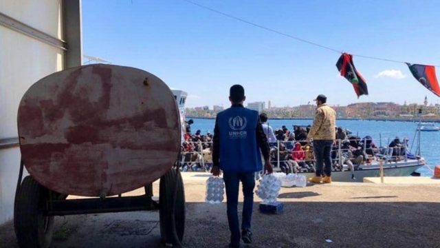 Le personnel du HCR distribue des bouteilles d'eau aux réfugiés et aux migrants dont le bateau a été intercepté alors qu'il tentait de traverser la Méditerranée, et qui a finalement été renvoyé en Libye le 9 avril