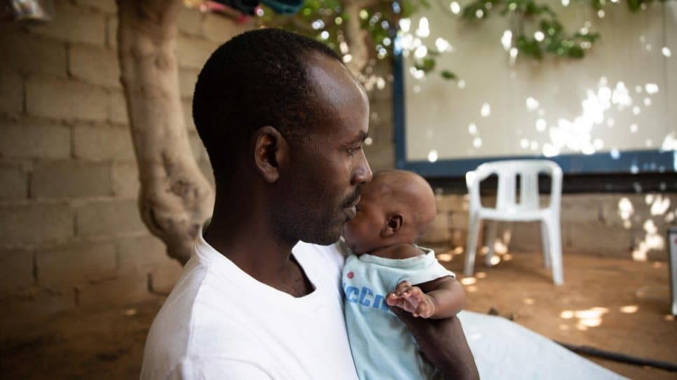 Sudanese refugee from Darfur, Abdulmajeed, holds his newborn daughter Afnan at home in Tripoli, Libya