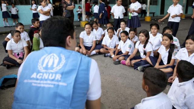 UNHCR senior child protection assistant Juan Camilo Jiménez talks in November, 2019, to children at the Simón Bolívar School in Tegucigalpa, Honduras, about forced displacement