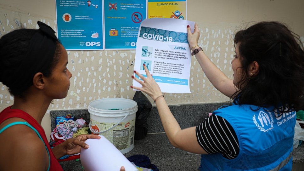 Une employée du HCR explique les directives de l'OMS pour prévenir la propagation de Covid-19 auprès des réfugiés et migrants vénézuéliens à Manaus, au Brésil