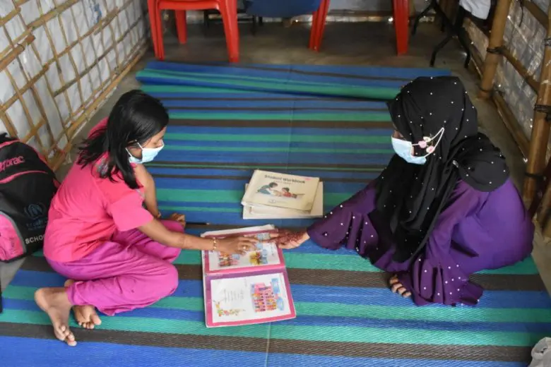 Nur Ayna (right) interacts with a Rohingya refugee student at Kutapalong refugee camp, Bangladesh