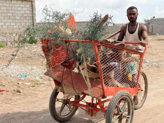 Man riding a tricycle filled with recycled material