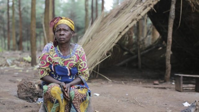 Emmanuelle, 56, from DRC sits outside the shelter where she slept for over a month after fleeing deadly violence in Ituri province, Uganda in late May