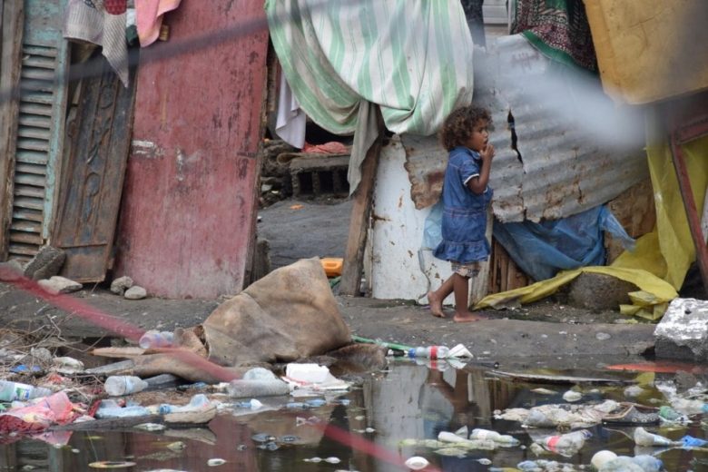 Une fillette marche le long d’une zone inondée dans un site de déplacés internes à Aden, au Yémen. Mars 2020