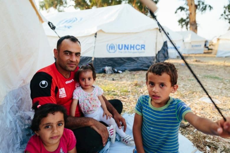 Syrian refugee Mohammed Sadik Jalani and his children sit beside tents set up by Greek authorities and UNHCR to provide shelter after fires destroyed the Moria Reception and Identification Centre on Lesvos