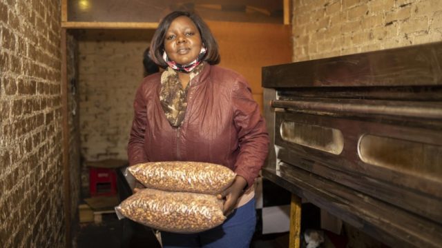 Grace, une réfugiée congolaise de 43 ans, transporte des sacs d’arachides grillées dans son entreprise à Pretoria, en Afrique du Sud.