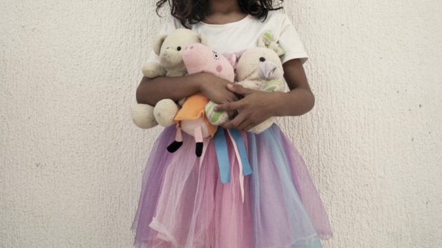 Une jeune fille tient ses oursons en peluche.