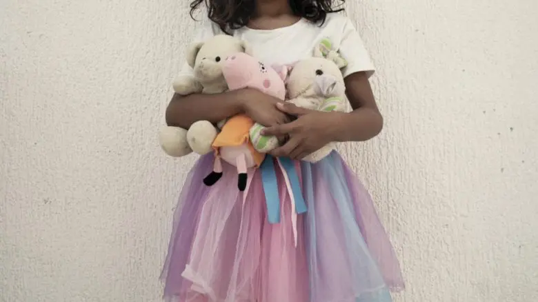 Young girl holding her dolls.