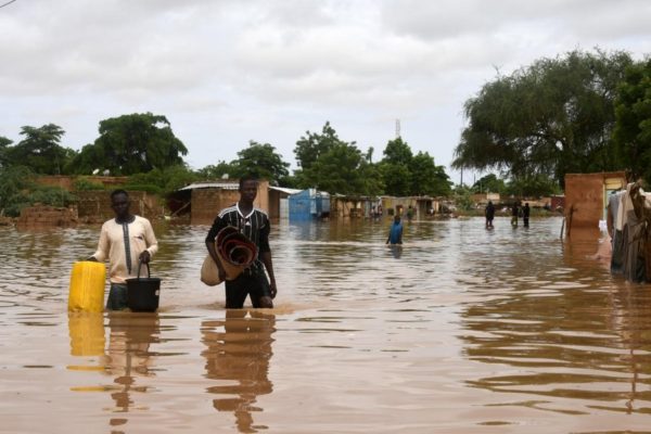 Des personnes transportent des effets personnels dans une rue inondée par le fleuve Niger.