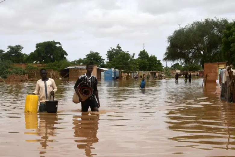 People carrying their belongings in a street flooded by the Niger River.