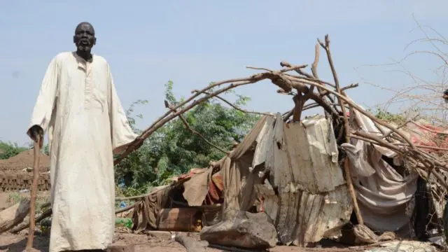 Bak, un réfugié sud-soudanais de 80 ans, se tient à côté de son abri qui a été endommagé par des inondations massives à Sharq Al-Nile, au Soudan.