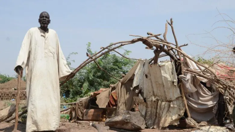 Bak, un réfugié sud-soudanais de 80 ans, se tient à côté de son abri qui a été endommagé par des inondations massives à Sharq Al-Nile, au Soudan.