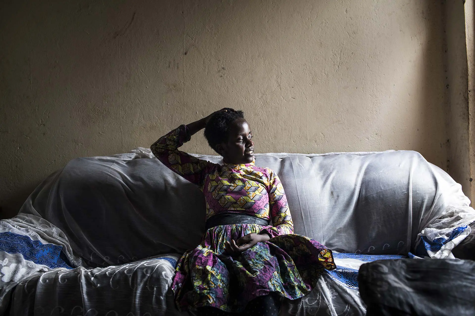 Jonaliese rests in her living room, in the back of her blacksmith workshop, in Rwamwanja, Uganda.