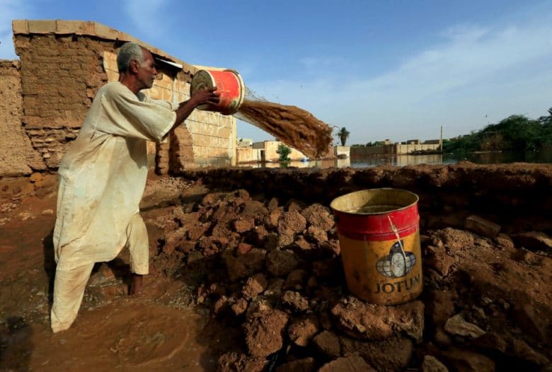 A resident pours removes buckets of waters from the Blue Nile floods within the Al-Ikmayr area of Omdurman in Khartoum