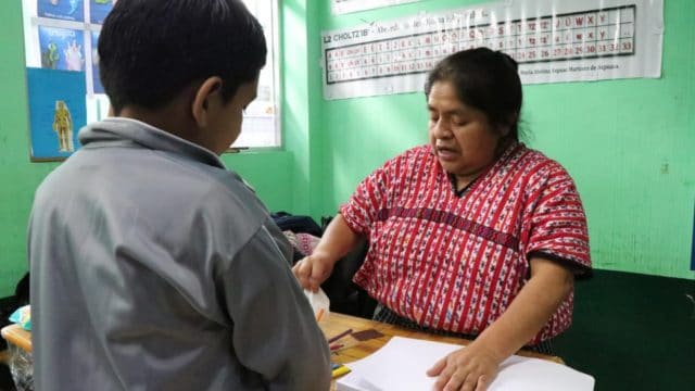 Le demandeur d’asile nicaraguayen Isai* (veste grise), âgé de huit ans, travaille avec son professeur de CE2 avant la fermeture de son école à la périphérie de Guatemala City