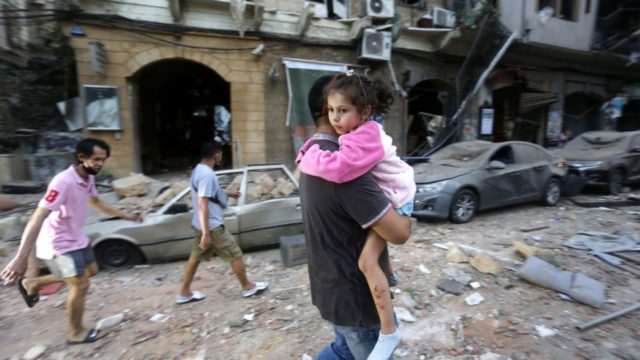 Un homme transporte une enfant blessée vers un lieu sûr à la suite d’une explosion massive dans le port de Beyrouth, au Liban