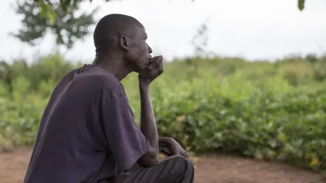 A South Sudanese refugee sits outside his shelter in Uganda's Bidibidi settlement.