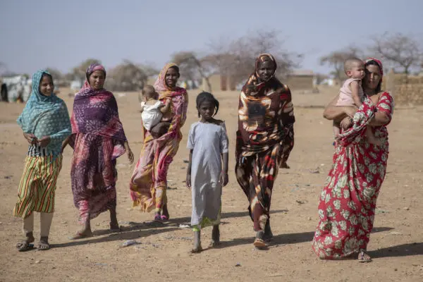 Malian refugees in Goudoubo camp carry home new dignity kits, received at a distribution point in the camp