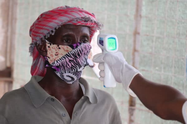 A refugee has his temperature taken before collecting his UNHCR and WFP food and aid package at Dadaab camp in Kenya