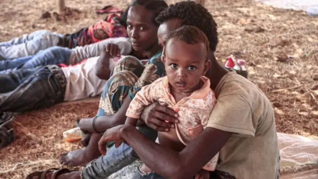 Un réfugié éthiopien tient un enfant sur ses genoux dans un abri du camp d'Um Rakuba, dans la province de Gedaref à l'est du Soudan.