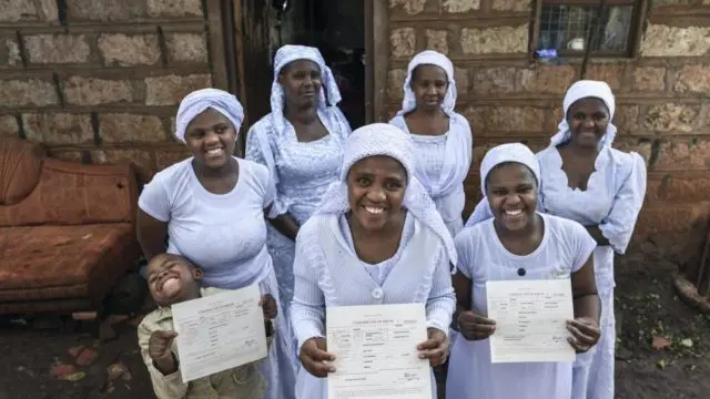 Stateless Shona woman, Nosizi Reuben (front-centre) poses with her family as she holds up her recently-issued birth certificate at home in Kinoo, Kenya