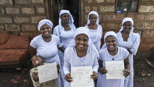 Nosizi Reuben (au premier plan), une femme apatride de la communauté Shona, pose avec sa famille alors qu'elle tient son certificat de naissance récemment délivré chez elle à Kinoo, au Kenya